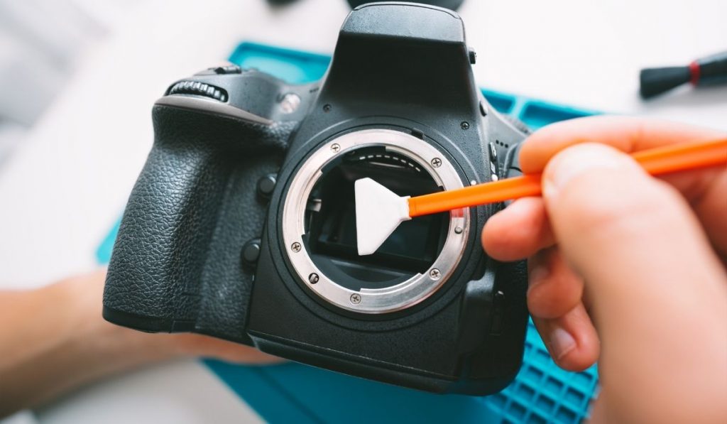 photographer cleaning the lense sensor of his camera - ee220330