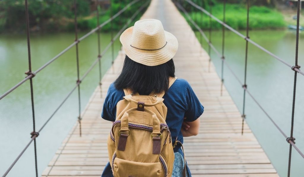 tourist at a river bridge wearing a backpack - ee220330