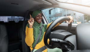 Happy-muslim-black-female-driver-singing-and-dancing-while-driving-car