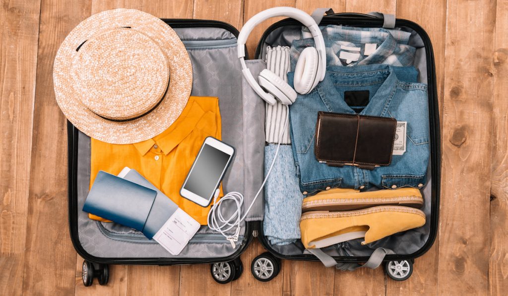 Top view of travel essentials for tourist with clothes, accessories and gadgets