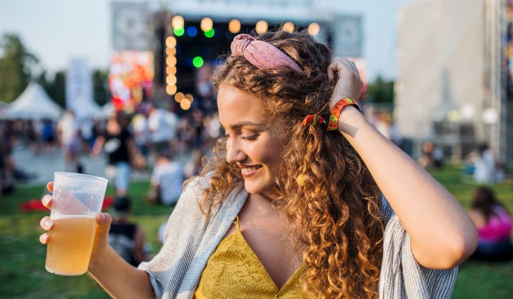 adult woman holding a drink and dancing at summer festival