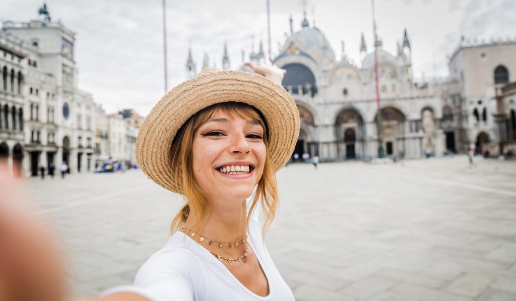 beautiful young woman smiling taking selfie travelling alone in Italy