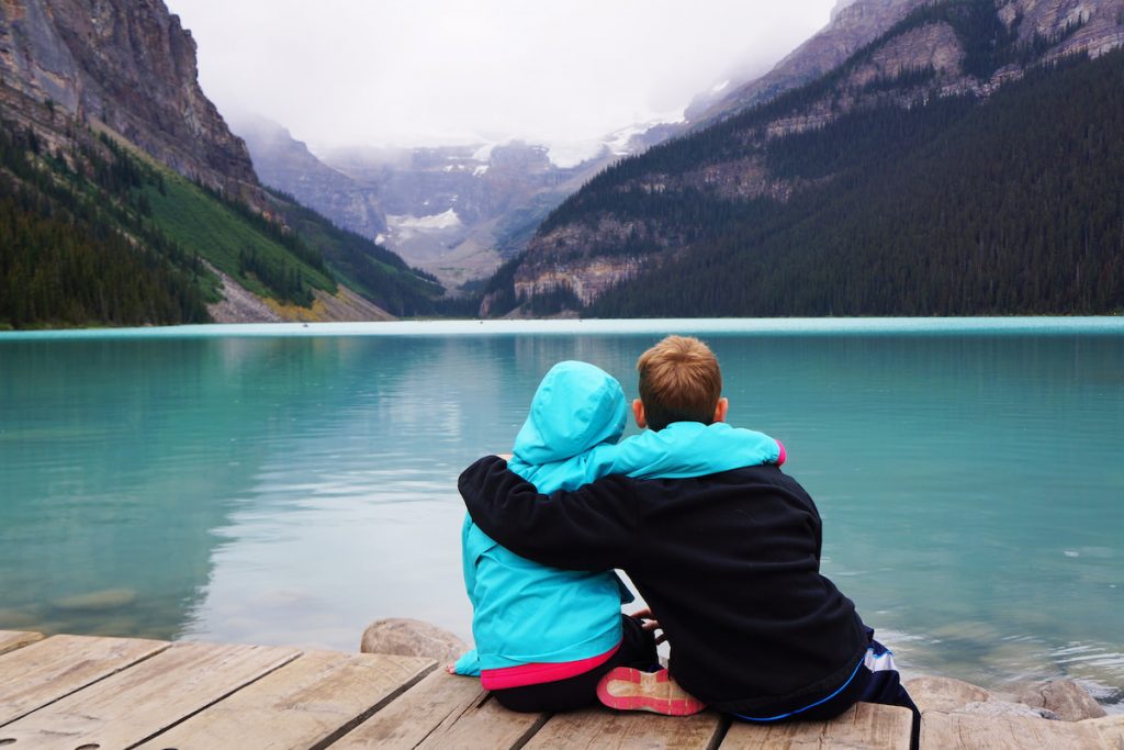 brother and sister sitting and looking at lake louise view