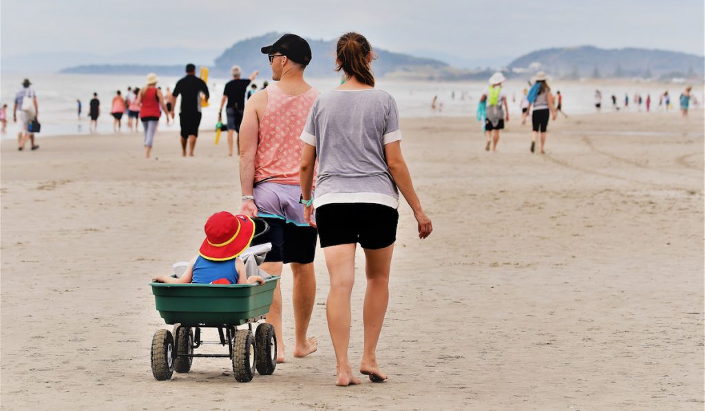 family walking during Summer at Waihi Beach, New Zealand