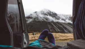 feet-with-violet-socks-of-solo-traveler-on-his-van-facing-mountain-in-new-zealand