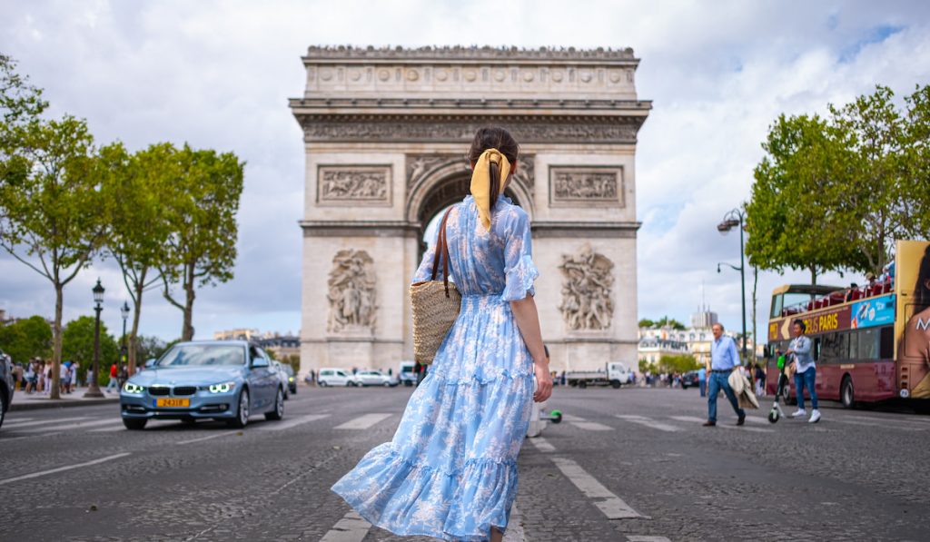 girl in blue dress standing against the arc de triomphe in Paris 