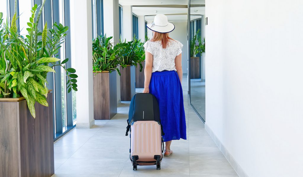girl tourist entering hotel with her suitcase