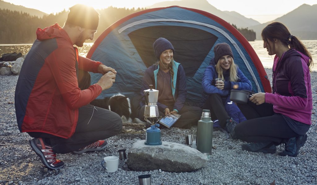 group of hikers camping at lakeshore sunset