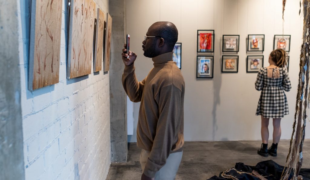 man capturing artwork using his phone in an art gallery