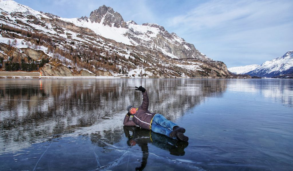 man on peace sign laying on a frozen lake 