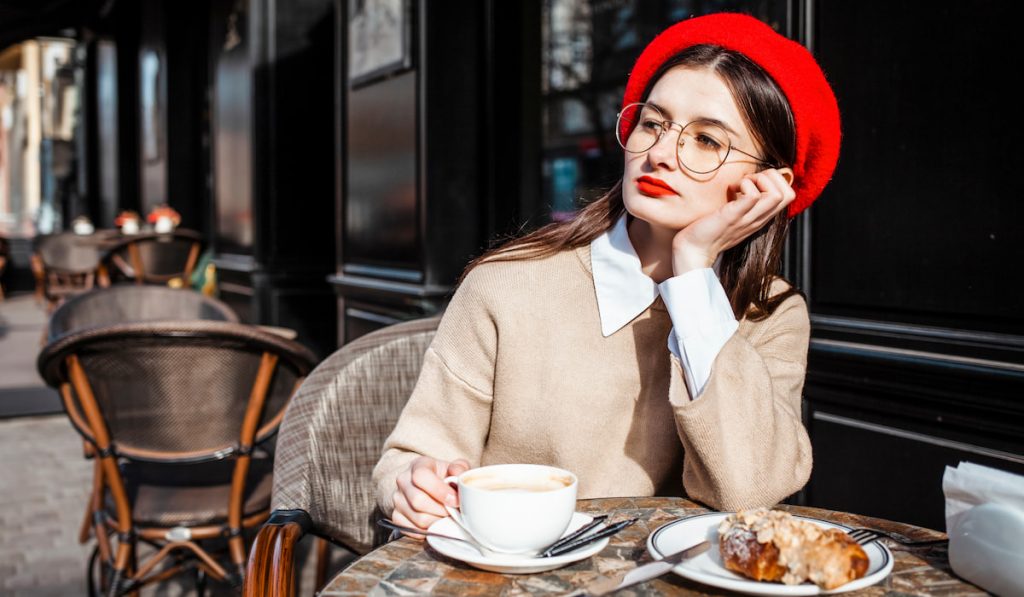 pretty lady sitting outide cafe shop outside with her coffee and bread 