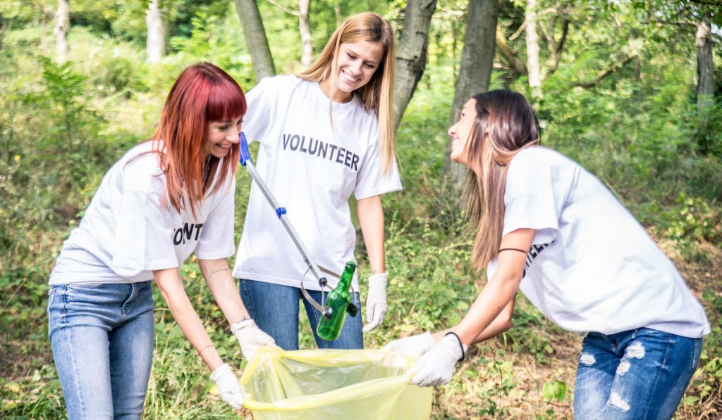 smiling volunteers cleaning garbage in the forest