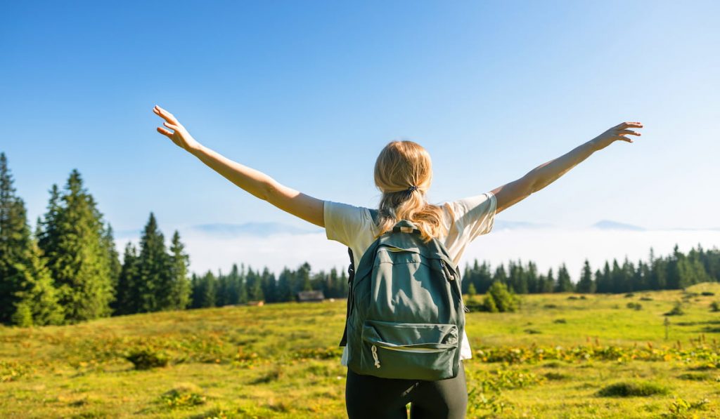 solo traveler enjoying her trip holding up her both arms in the air