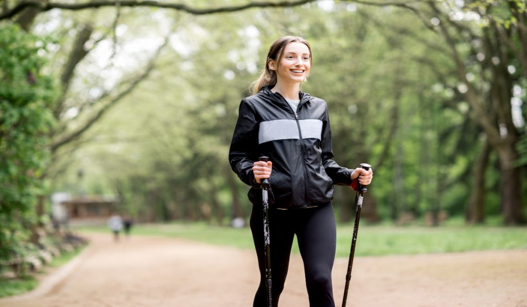 solo woman traveler walking with hiking sticks 