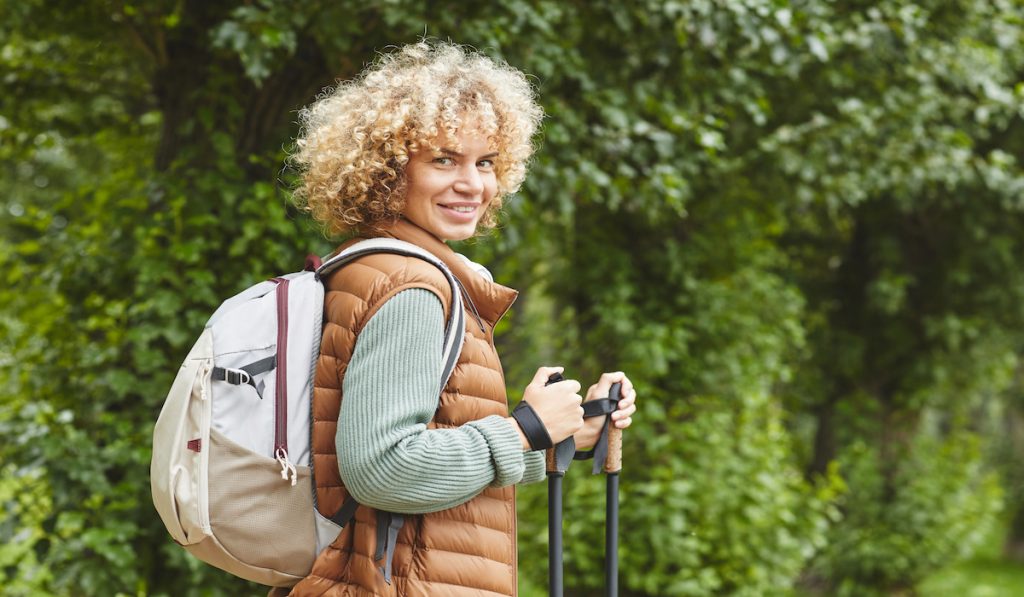 woman hiking alone holding hiking sticks