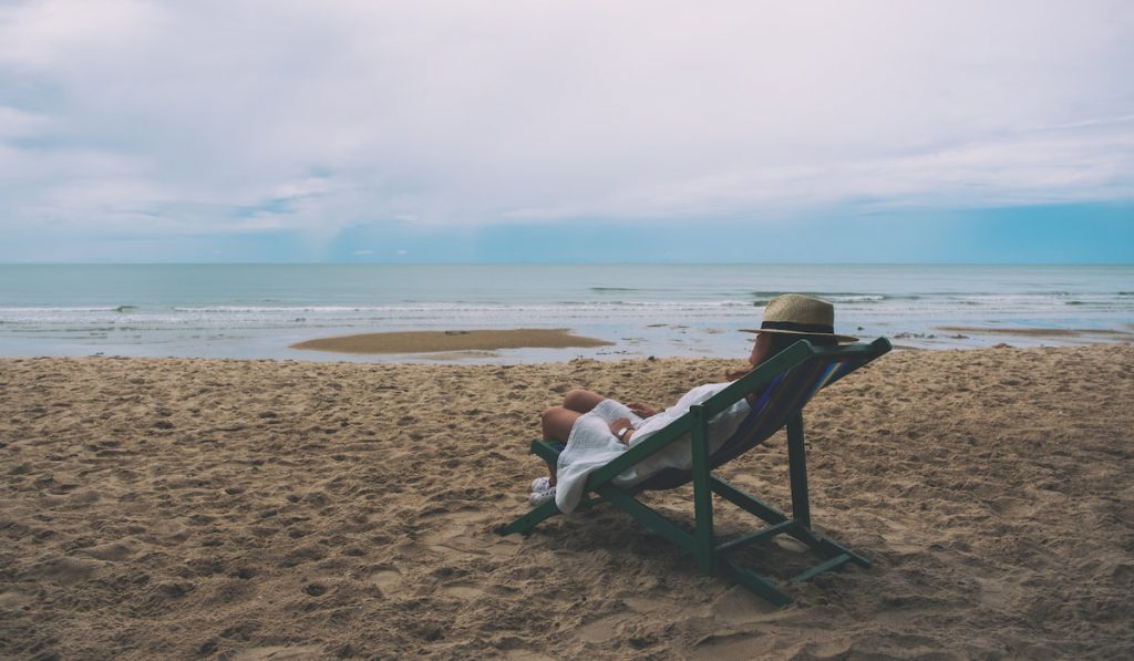 woman lying dow on a beach chair alone