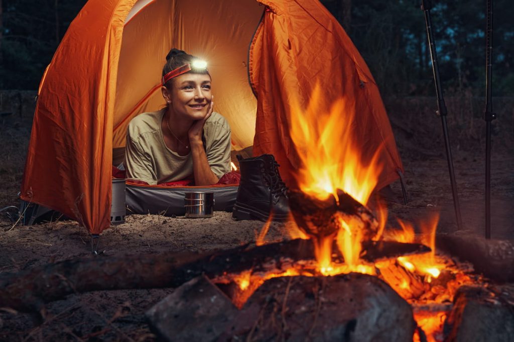 woman lying in her tent with headlight