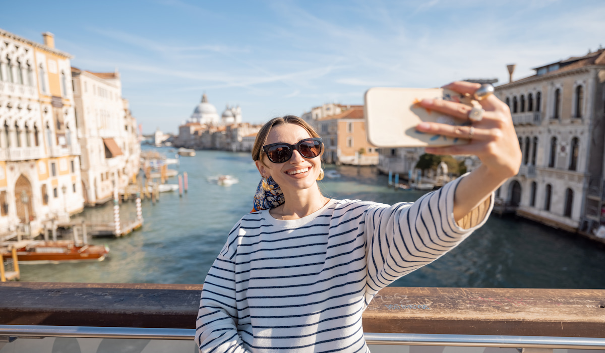 woman traveler taking a selfie on a bridge in venice, italy