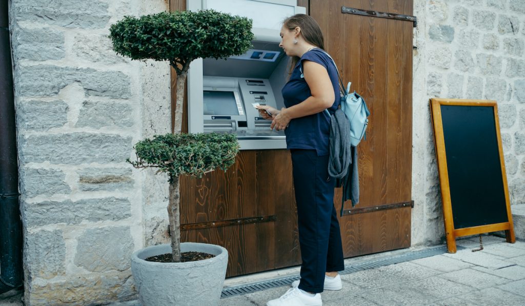 woman traveler withdrawing cash from ATM outside the country