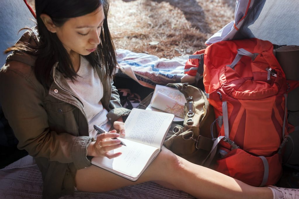 woman writing on her journal inside a tent