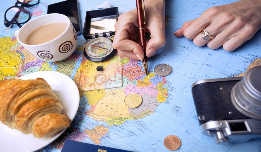 woman's hand holding a pen pointing on the map, planning a trip