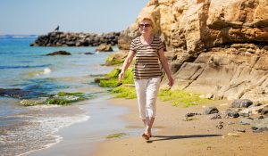 Happy elderly woman enjoying her walk along the seashore