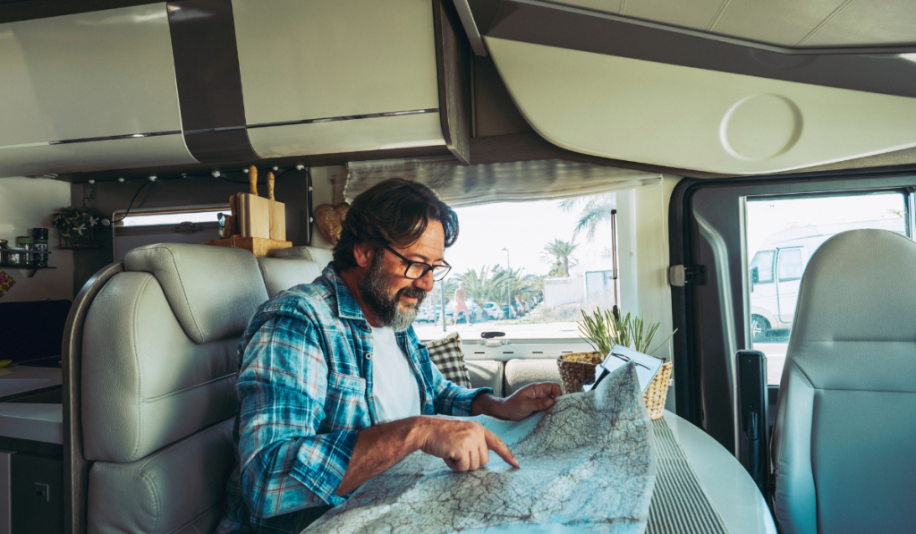 Nomadic traveler lifestyle adult mature man inside a camper van planning travel next destination
