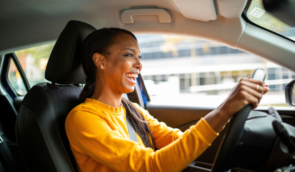 Portrait of joyful young african american woman driving a car
